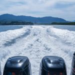 Four Boat motors left a pass of foam on the water .